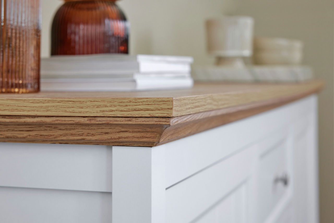 Nahaufnahme eines weißen Sideboards mit Holzplatte, dekoriert mit Büchern und Vasen, seitliche Perspektive