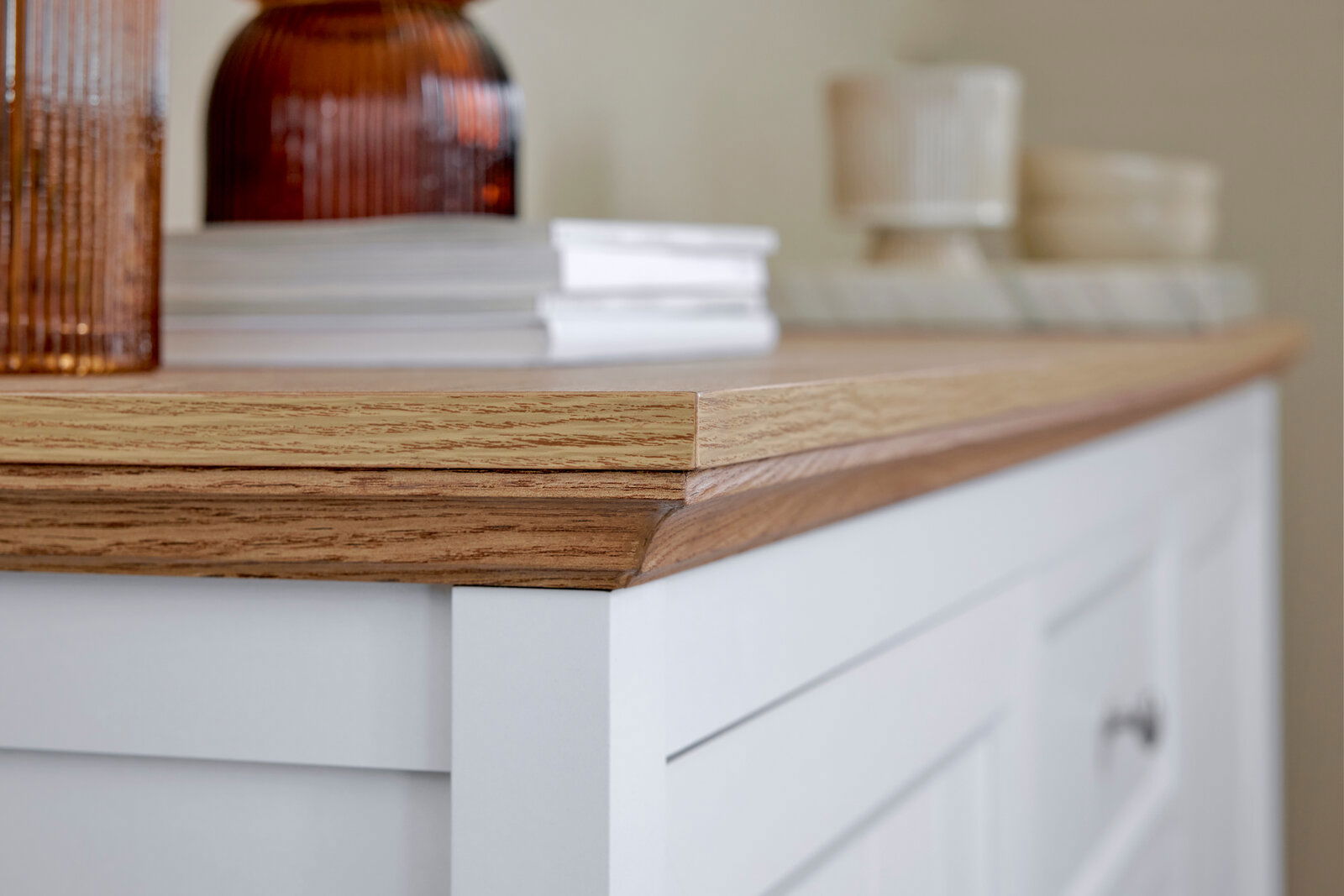 Nahaufnahme eines weißen Sideboards mit Holzplatte, dekoriert mit Büchern und Vasen, seitliche Perspektive