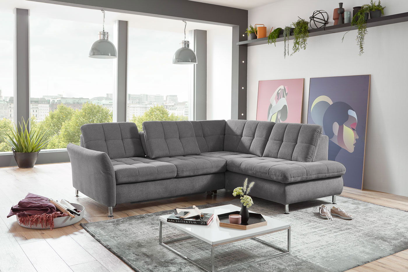 Graues Ecksofa Beldomo Style DRESDEN in modernem Wohnzimmer mit großen Fenstern und stilvoller Dekoration, seitliche Perspektive.