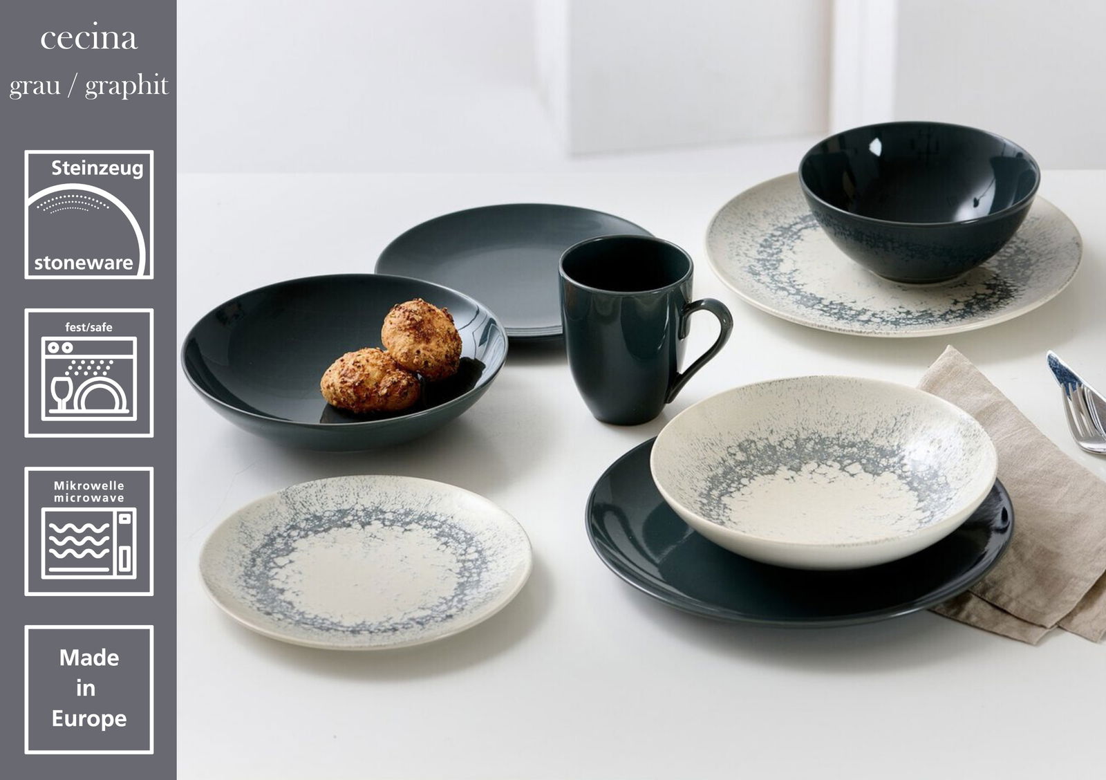 Steinzeug-Geschirrset Cecina in Grau/Graphit, bestehend aus flachen und tiefen Tellern, Schalen und einem Kaffeebecher, auf einem Tisch arrangiert. Perspektive von oben.