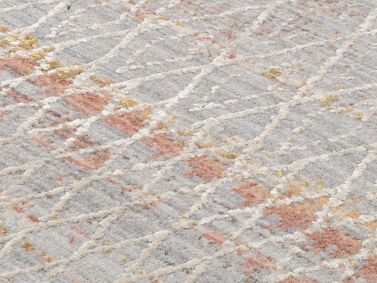 Nahaufnahme eines Designer Teppichs mit abstraktem Muster in Grau, Rot und Gelb. Perspektive von oben.