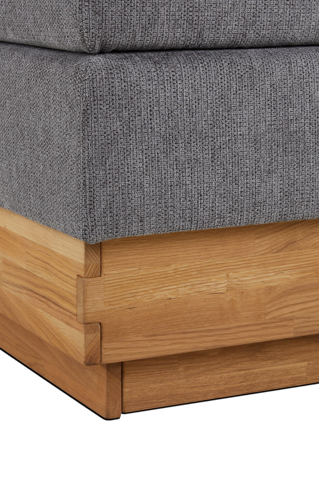 Nahaufnahme eines Boxspringbettes mit grauem Stoffbezug und Holzrahmen, Perspektive von der Ecke