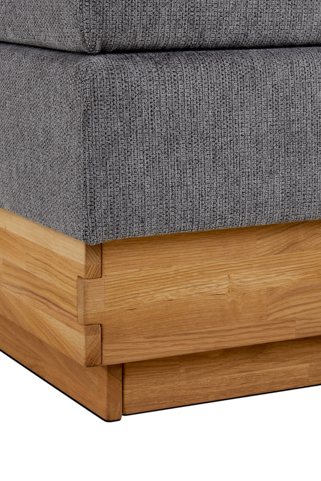 Nahaufnahme eines Boxspringbettes mit grauem Stoffbezug und Holzrahmen, Perspektive von der Ecke