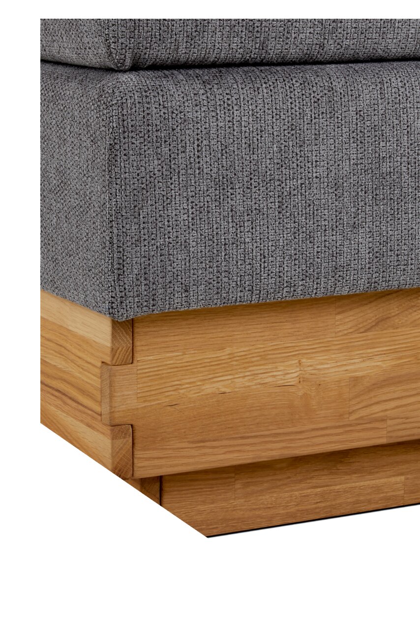 Nahaufnahme eines Boxspringbettes mit grauem Stoffbezug und Holzrahmen, Perspektive von der Ecke
