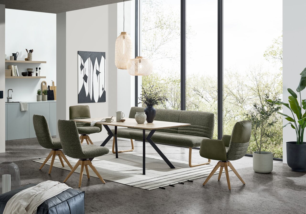 Moderner Esstisch 180x100cm mit grünen Stühlen und Bank in einem hellen Raum mit großen Fenstern, seitliche Perspektive.