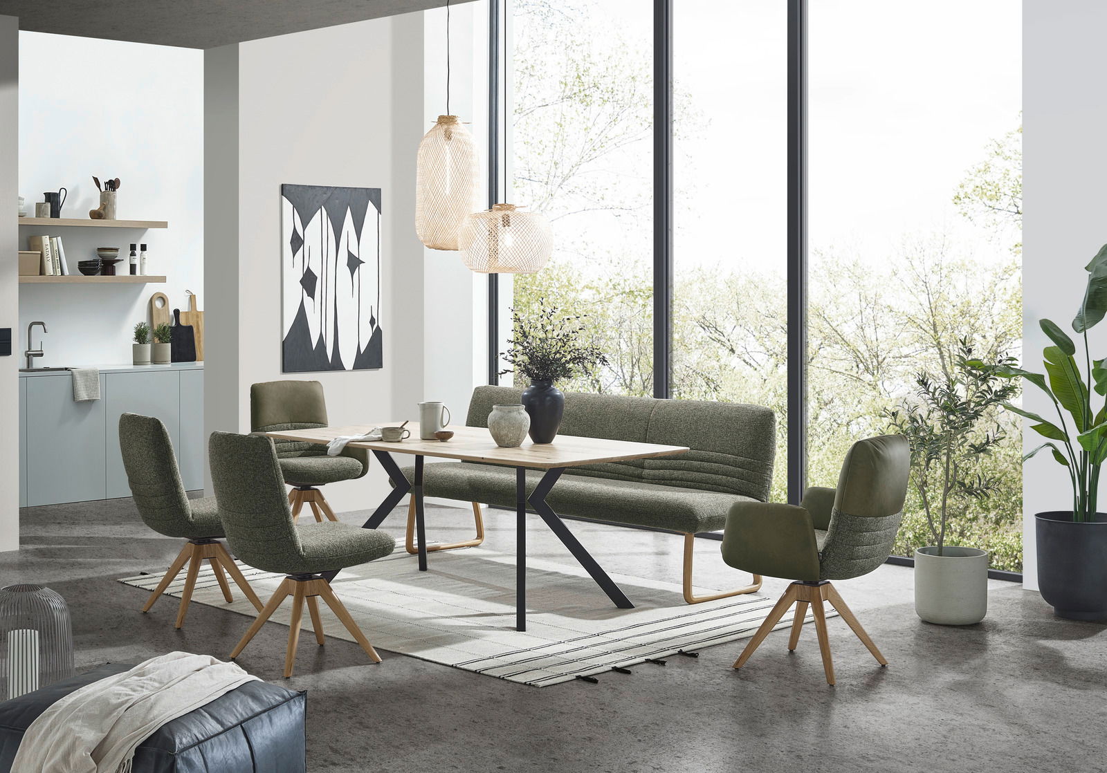 Moderner Esstisch 150x90cm mit Holzplatte und schwarzen Metallbeinen, umgeben von grünen Stühlen und einer Bank, in einem hellen Raum mit großen Fenstern, aus der Perspektive von vorne.