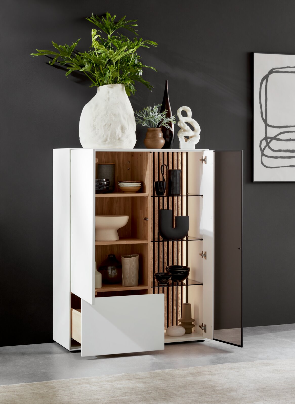 Modernes Highboard mit Glas rechts, dekoriert mit Vasen und Pflanzen, aus einer leicht seitlichen Perspektive fotografiert.