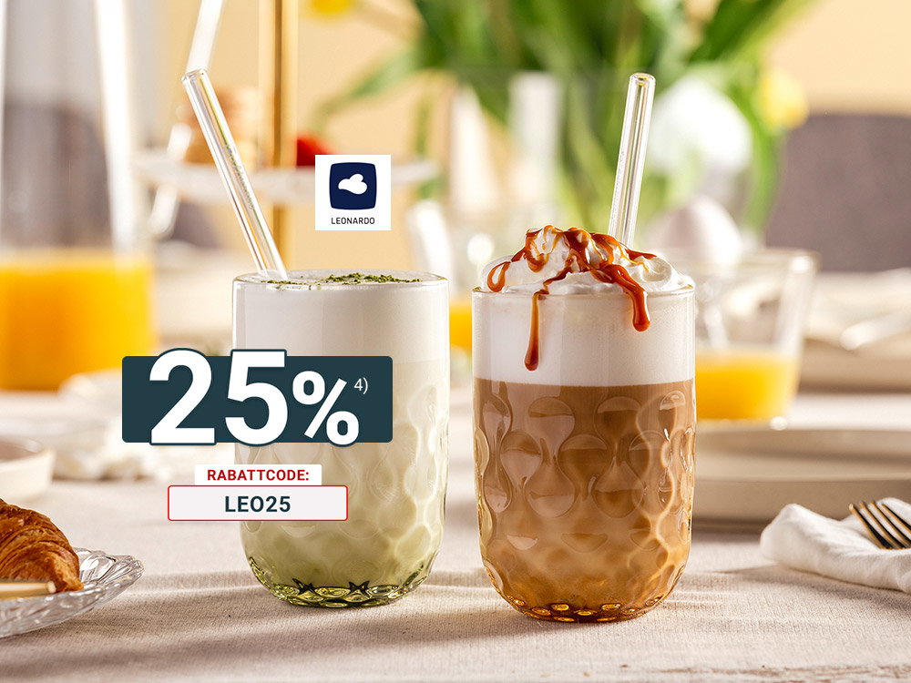 Zwei Latte-Getränke im strukturierten Glas – Matcha Latte und Caramel Latte mit Sahne – auf gedecktem Frühstückstisch mit Croissant und Orangensaft