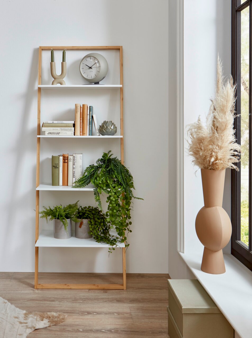 Modernes Leiterregal aus hellem Holz mit weißen Ablagen, dekoriert mit Büchern, Pflanzen und Uhr, in heller Wohnraumszene; Perspektive: frontale Ansicht auf Augenhöhe.