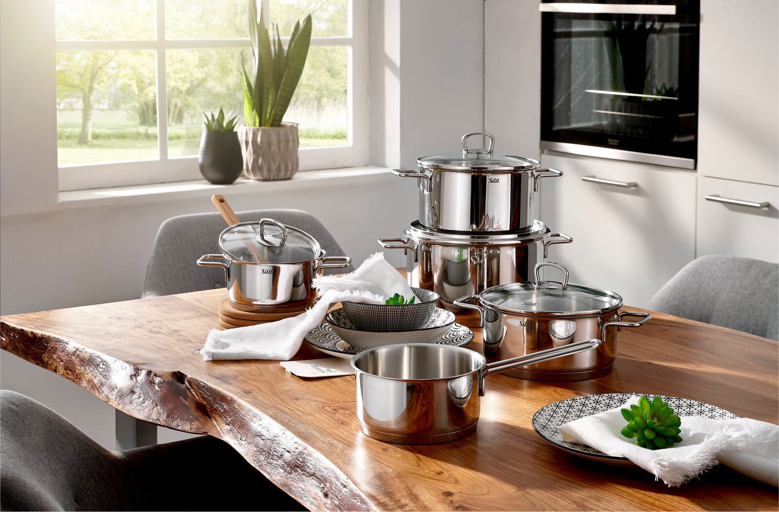 Topfset Alicante 5-tlg aus Edelstahl auf einem Holztisch in einer modernen Küche, seitliche Perspektive