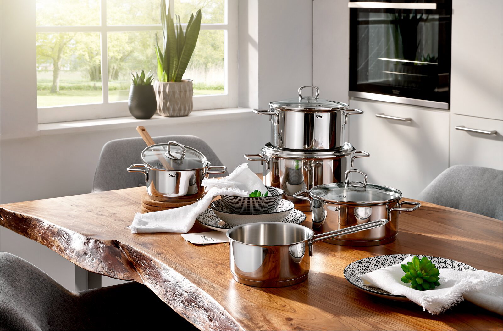 Topfset Alicante 5-tlg aus Edelstahl auf einem Holztisch in einer modernen Küche, seitliche Perspektive