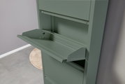 Schlanker, olivgrüner Metallschrank mit nach vorn aufgeklappter Klappe/Schreibfläche, gezeigt in schräger Seitenansicht von vorn rechts.