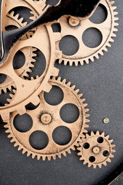 Nahaufnahme einer Wanduhr mit sichtbaren Zahnrädern in einem industriellen Design.