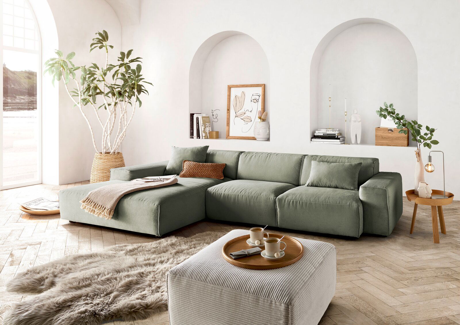 Grünes Ecksofa in modernem Wohnzimmer mit großen Fenstern, Pflanzen und stilvollen Dekorationen, seitliche Perspektive.