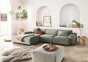 Grünes Ecksofa in modernem Wohnzimmer mit großen Fenstern, Pflanzen und stilvollen Dekorationen, seitliche Perspektive.