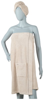 Wellnessset van beige badstof, bestaande uit een wikkelhanddoek met zakje en een bijpassende turban, vooraan op een etalagepop gepresenteerd.