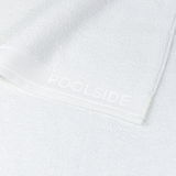 Nahaufnahme eines weißen Handtuchs mit der Aufschrift 'POOLSIDE' auf dem Rand.