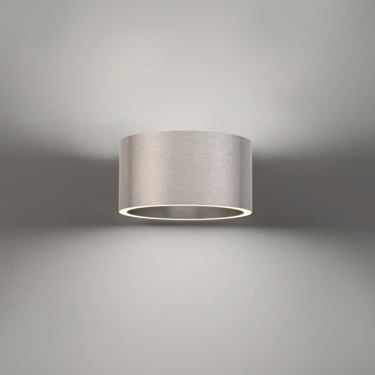 Moderne Wandleuchte PURE Clipse in zylindrischer Form aus gebürstetem Metall, Ansicht von vorne.