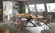 Esszimmer mit modernem Armlehnstuhl in Beige, um einen ovalen Holztisch mit schwarzem Metallgestell, seitliche Perspektive