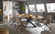 Esszimmer mit modernem Armlehnstuhl in Beige, um einen ovalen Holztisch mit schwarzem Metallgestell, seitliche Perspektive