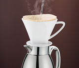 Seitliche Ansicht einer Isolierkanne Venezia aus Edelstahl mit einem weißen Kaffeefilteraufsatz, in den heißes Wasser gegossen wird.