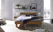 Frontale Ansicht eines modernen Bettes mit Kopfteil aus Holz und Metall, umgeben von stilvoller Dekoration in einem hellen Schlafzimmer.