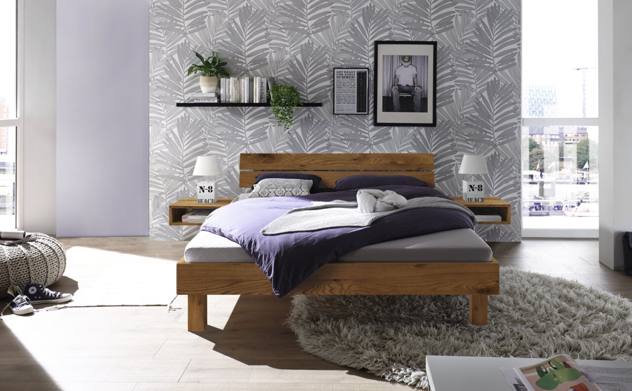 Frontale Ansicht eines modernen Bettes mit Kopfteil aus Holz und Metall, umgeben von stilvoller Dekoration in einem hellen Schlafzimmer.