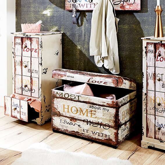 Zurbrüggen Sitztruhe DROPSHIPPING Rustikale Aufbewahrungstruhe aus Holz im Vintage-Shabby-Chic mit Klappdeckel und Schriftzug „HOME“, in seitlicher Perspektive auf dem Boden inszeniert.