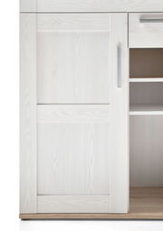 Detailansicht eines weißen Barschrankes mit Holzmaserung und silbernem Griff, teilweise geöffnete Tür mit Regalfächern sichtbar.