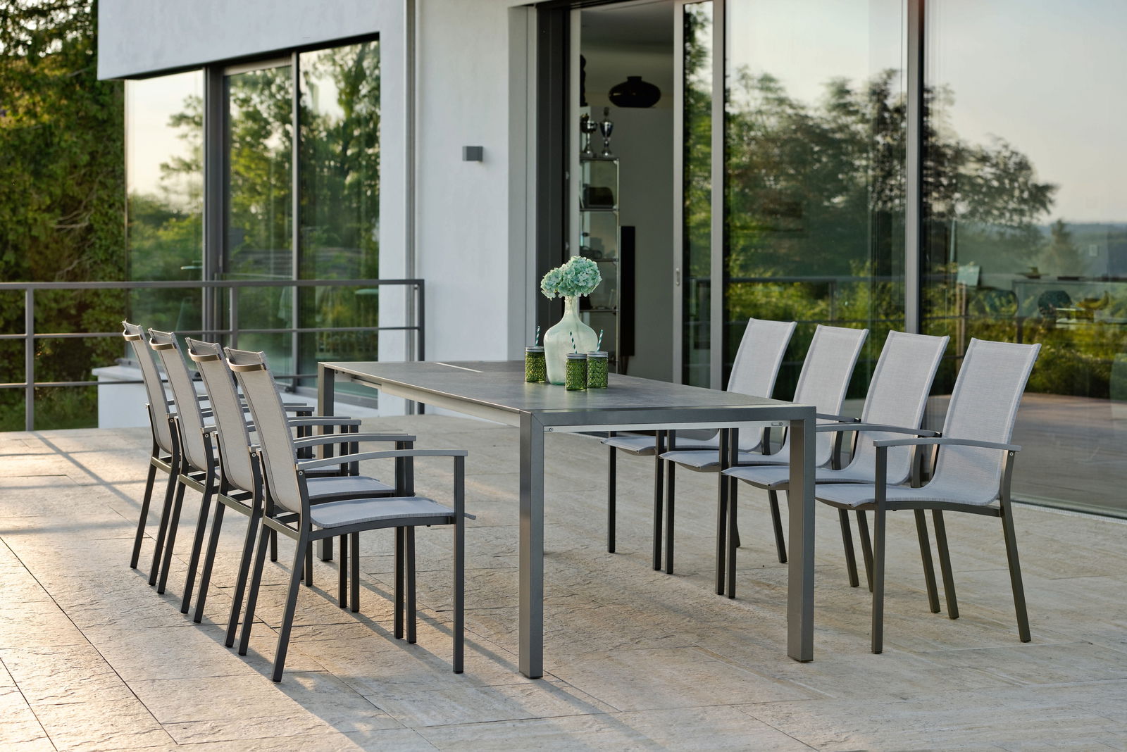 Moderner Stapelsessel auf einer Terrasse, seitliche Perspektive mit Blick auf einen Tisch und mehrere Stühle.