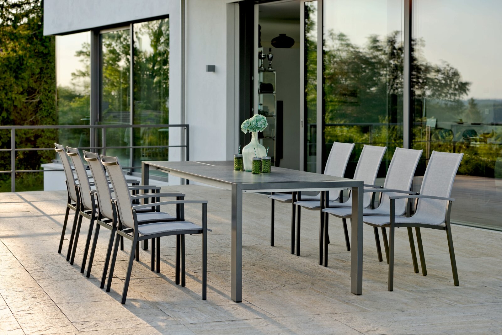 Moderner Stapelsessel auf einer Terrasse, seitliche Perspektive mit Blick auf einen Tisch und mehrere Stühle.
