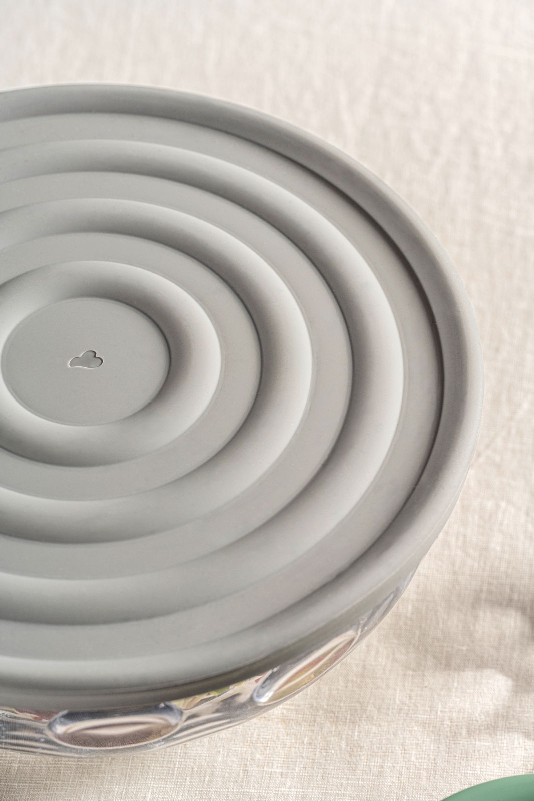 Grauer Silikondeckel mit konzentrischen Kreisen, von oben betrachtet, auf einer Glasschüssel.