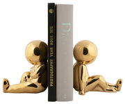 Zwei goldene Buchstützen in Form von sitzenden Figuren, die Bücher aufrecht halten. Perspektive von der Seite.
