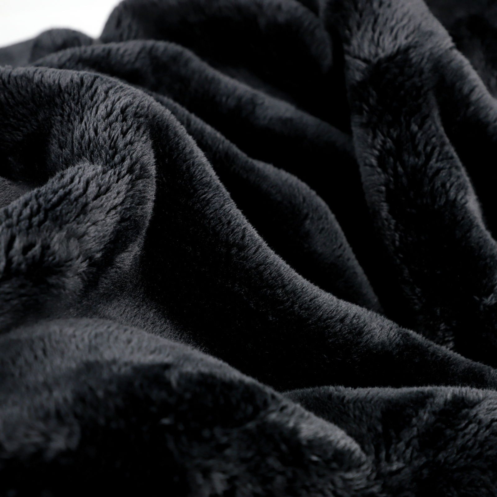 Nahaufnahme einer weichen, schwarzen Wohndecke mit flauschiger Textur.