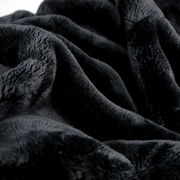 Nahaufnahme einer weichen, schwarzen Wohndecke mit flauschiger Textur.