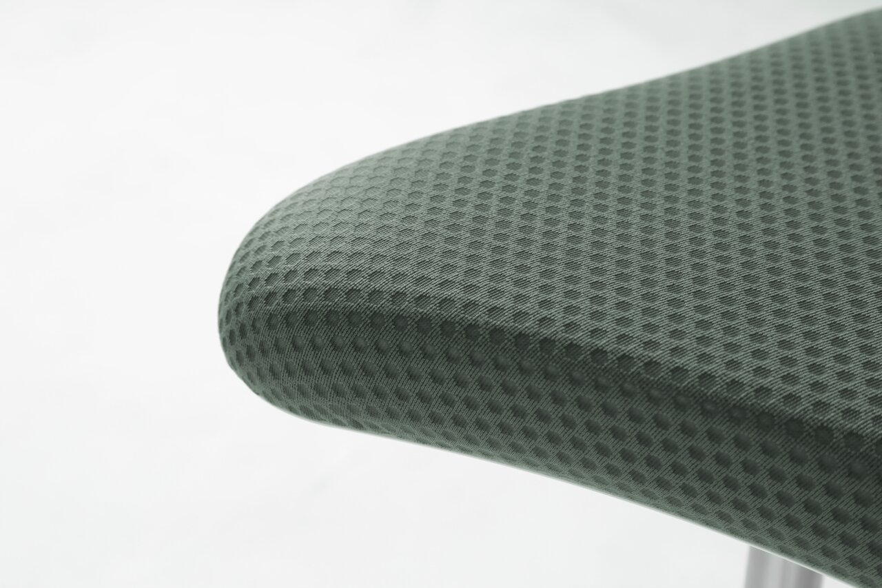 Close-up van een schommelstoel met een grijze, gestructureerde stoffen bekleding, gezien vanaf de zijkant
