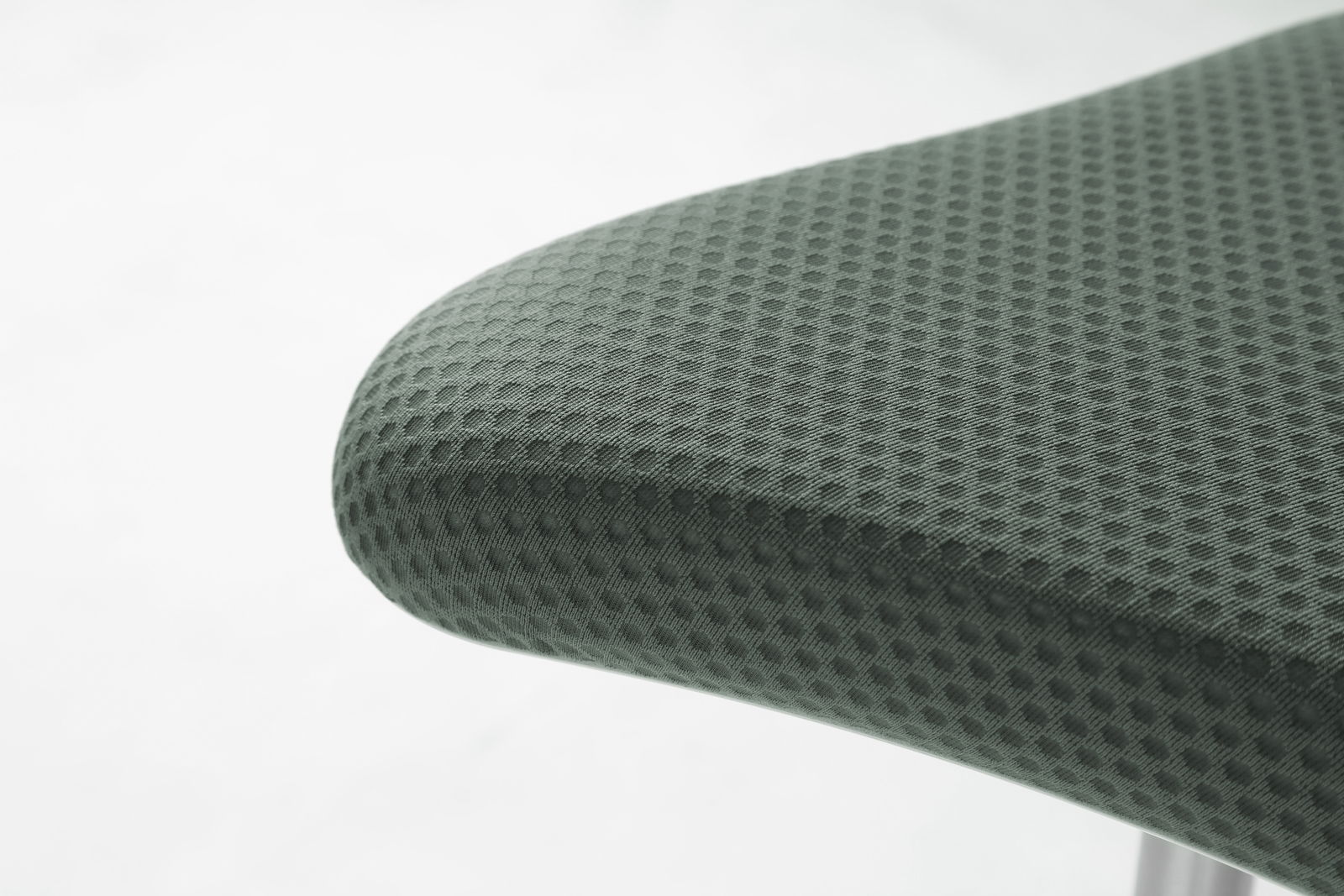 Nahaufnahme eines Schwinghockers mit grauem, texturiertem Stoffbezug, seitliche Perspektive