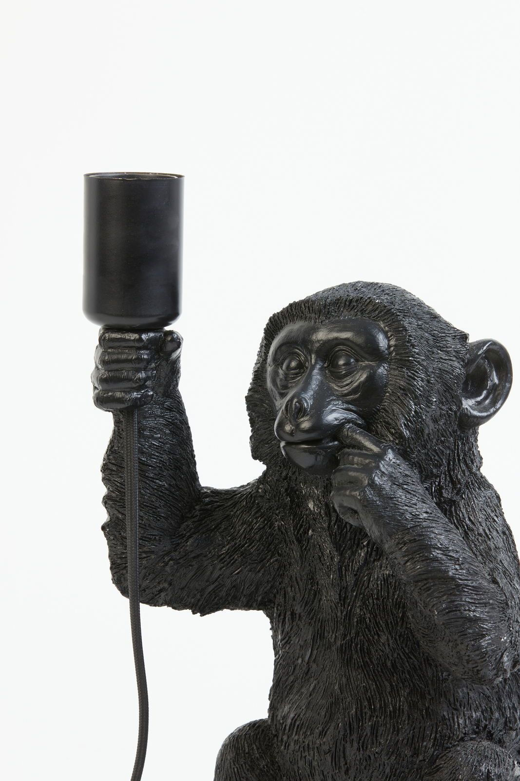 Nahaufnahme einer schwarzen Tischleuchte in Form eines Affen, der eine Lampe in der Hand hält.