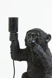 Nahaufnahme einer schwarzen Tischleuchte in Form eines Affen, der eine Lampe in der Hand hält.