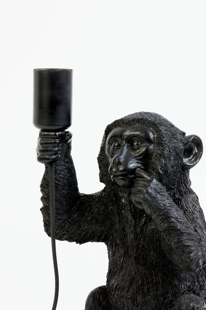 Nahaufnahme einer schwarzen Tischleuchte in Form eines Affen, der eine Lampe in der Hand hält.