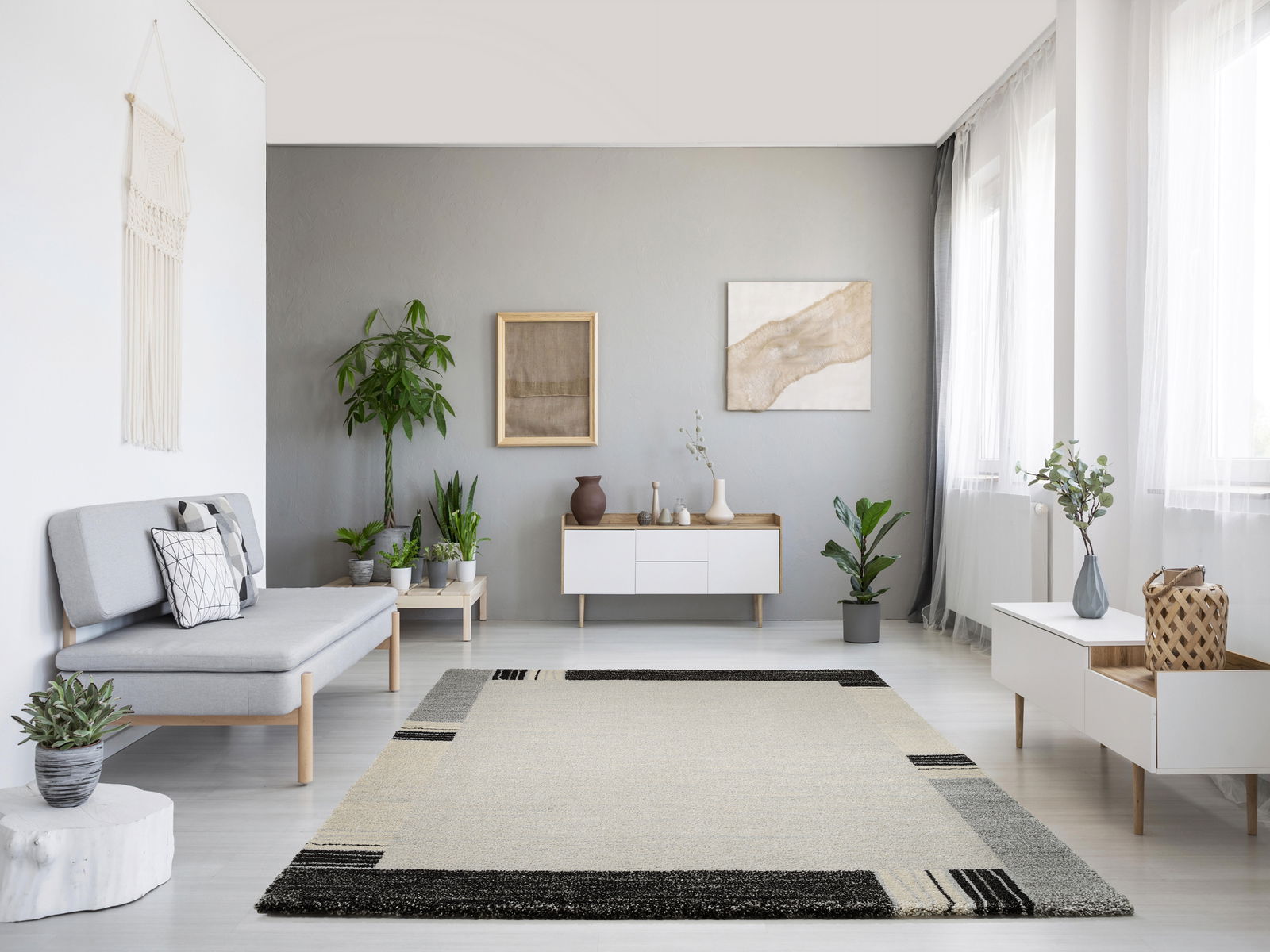 Moderner Wohnzimmerteppich in neutralen Farben mit geometrischem Muster, zentral im Raum platziert, umgeben von minimalistischen Möbeln und Pflanzen, aus der Vogelperspektive betrachtet.