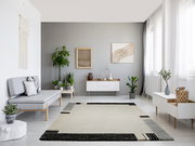 Moderner Wohnzimmerteppich in neutralen Farben mit geometrischem Muster, zentral im Raum platziert, umgeben von minimalistischen Möbeln und Pflanzen, aus der Vogelperspektive betrachtet.