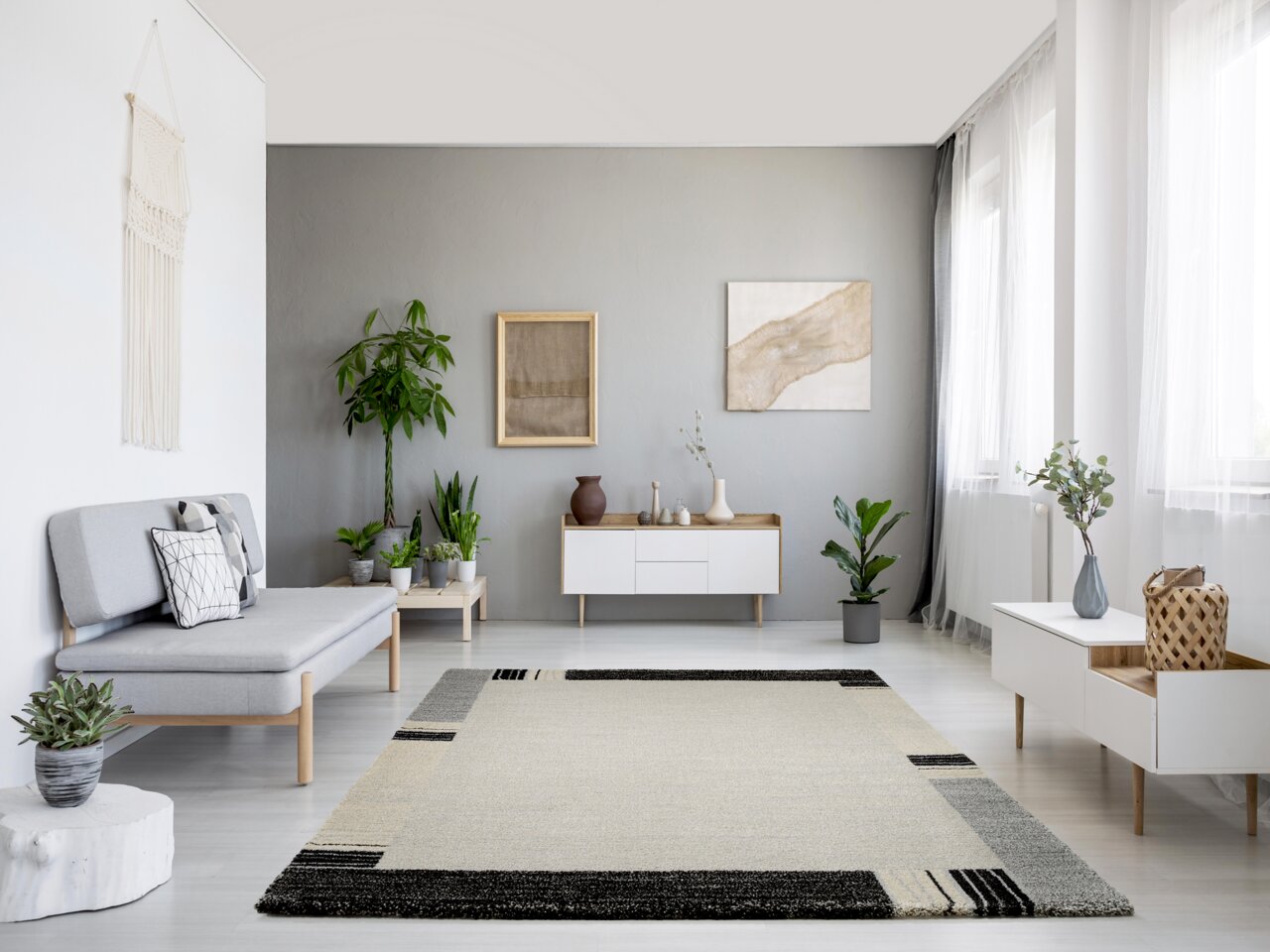 Moderner Wohnzimmerteppich in neutralen Farben mit geometrischem Muster, zentral im Raum platziert, umgeben von minimalistischen Möbeln und Pflanzen, aus der Vogelperspektive betrachtet.