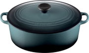 Ovaler Le Creuset Bräter in Petrol mit passendem Deckel, schwarzem Deckelknauf und zwei Seitengriffen, aus leicht erhöhter Frontperspektive vor weißem Hintergrund