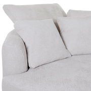 Nahaufnahme einer hellgrauen Rundecke mit Ottomane links, zwei großen Rückenkissen und einem kleineren Kissen, aus weichem Stoff.