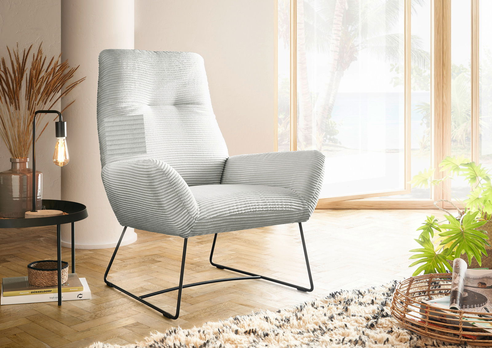 Lounge Handmade Sessel LH-BEN Moderner Sessel in hellgrauem Stoff mit Metallbeinen, seitliche Perspektive, in einem hellen Raum mit großen Fenstern und Pflanzen.