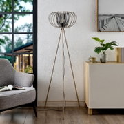 Moderne staande lamp met driepoot en decoratieve lampenkap in een stijlvolle woonkamer, gezien vanaf de zijkant.