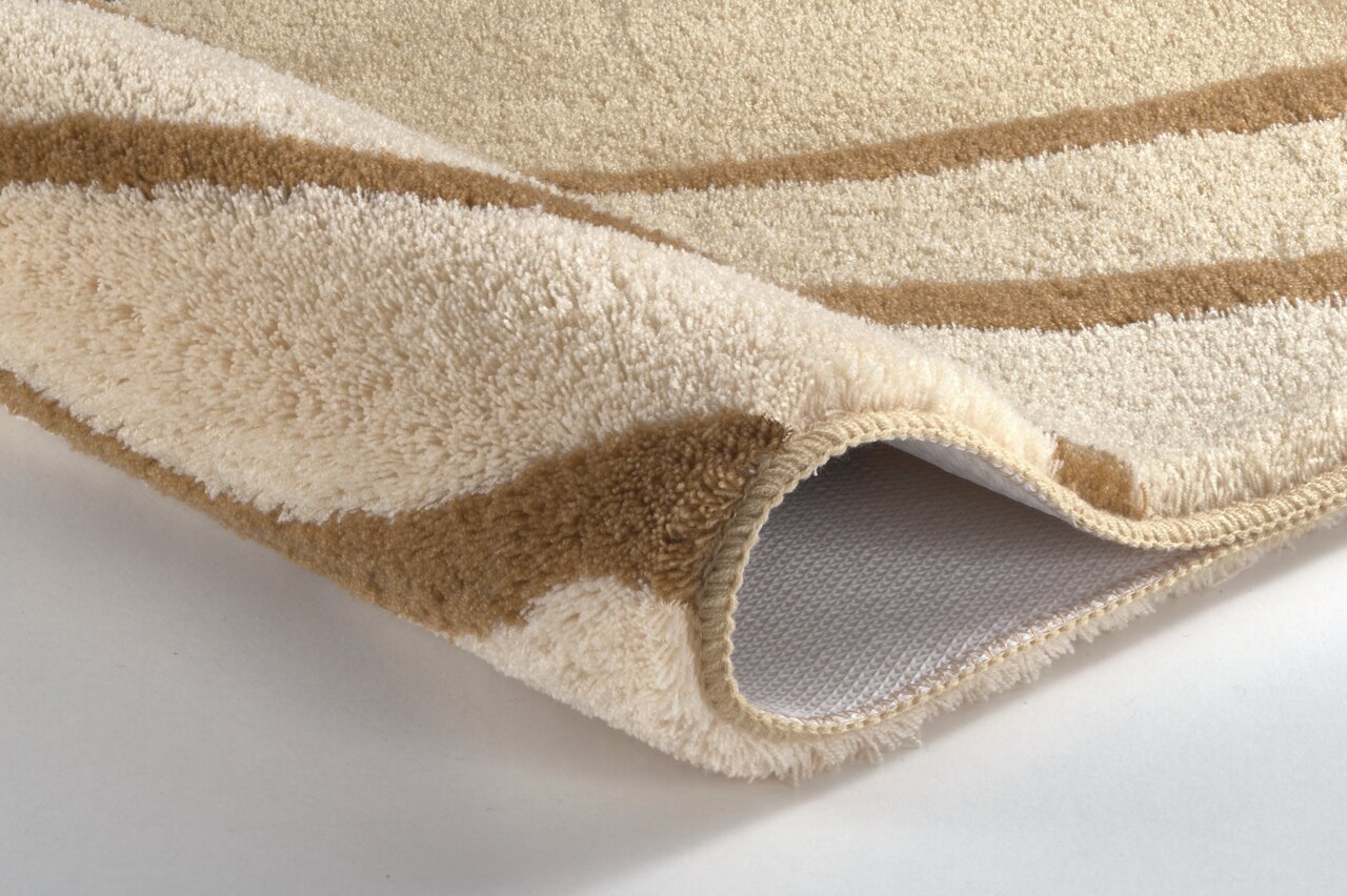 Kleine Wolke Badteppich JULIE Nahaufnahme eines beigen und braunen Badteppichs mit weicher Textur und rutschfester Unterseite, perspektivisch von der Seite aufgenommen.