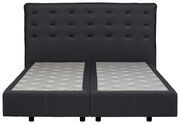 Frontale Ansicht eines modernen Boxspringbetts mit dunkelgrauem, gepolstertem Kopfteil und zwei Matratzen.
