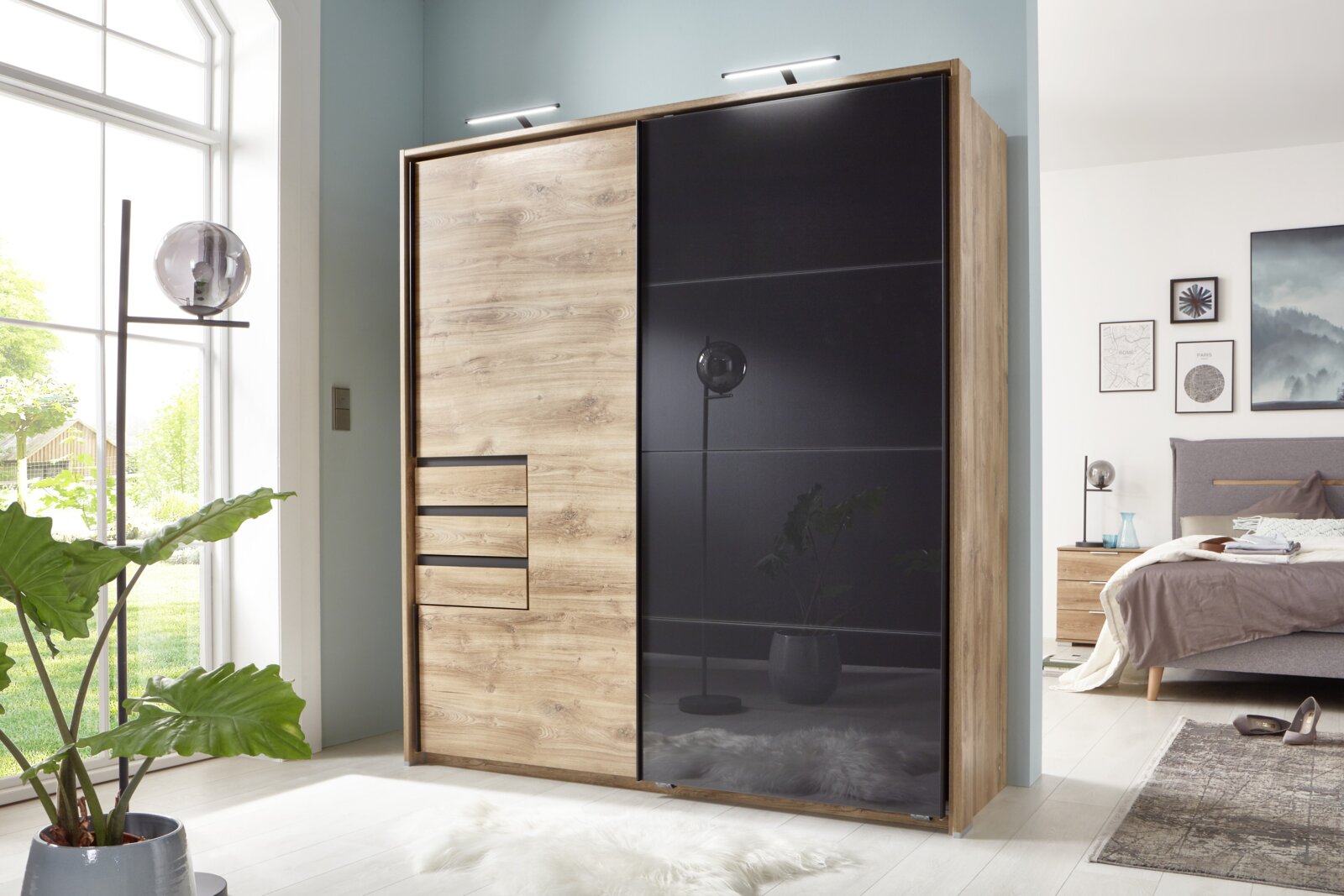 Z2 Passe-partout OLDENBURG Moderne kledingkast met houten en glazen elementen, gefotografeerd vanaf de voorkant in een lichte slaapkamer.